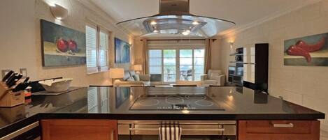 A modern kitchen with a central island, stainless steel appliances, and artwork on the walls.