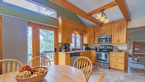 Une cuisine avec des meubles de rangement en bois, un four à micro-ondes et une table à manger avec des chaises.