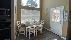 A dining area with a table and chairs, a window with blinds, a door with a sign, and a kitchen area with appliances. -  Weclome to Knot Shore  on Lake Texoma with boat parking (Pottsboro)