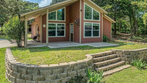 A two-story house with a covered porch, a stone retaining wall, and a grassy yard. -  Weclome to Knot Shore  on Lake Texoma with boat parking (Pottsboro)