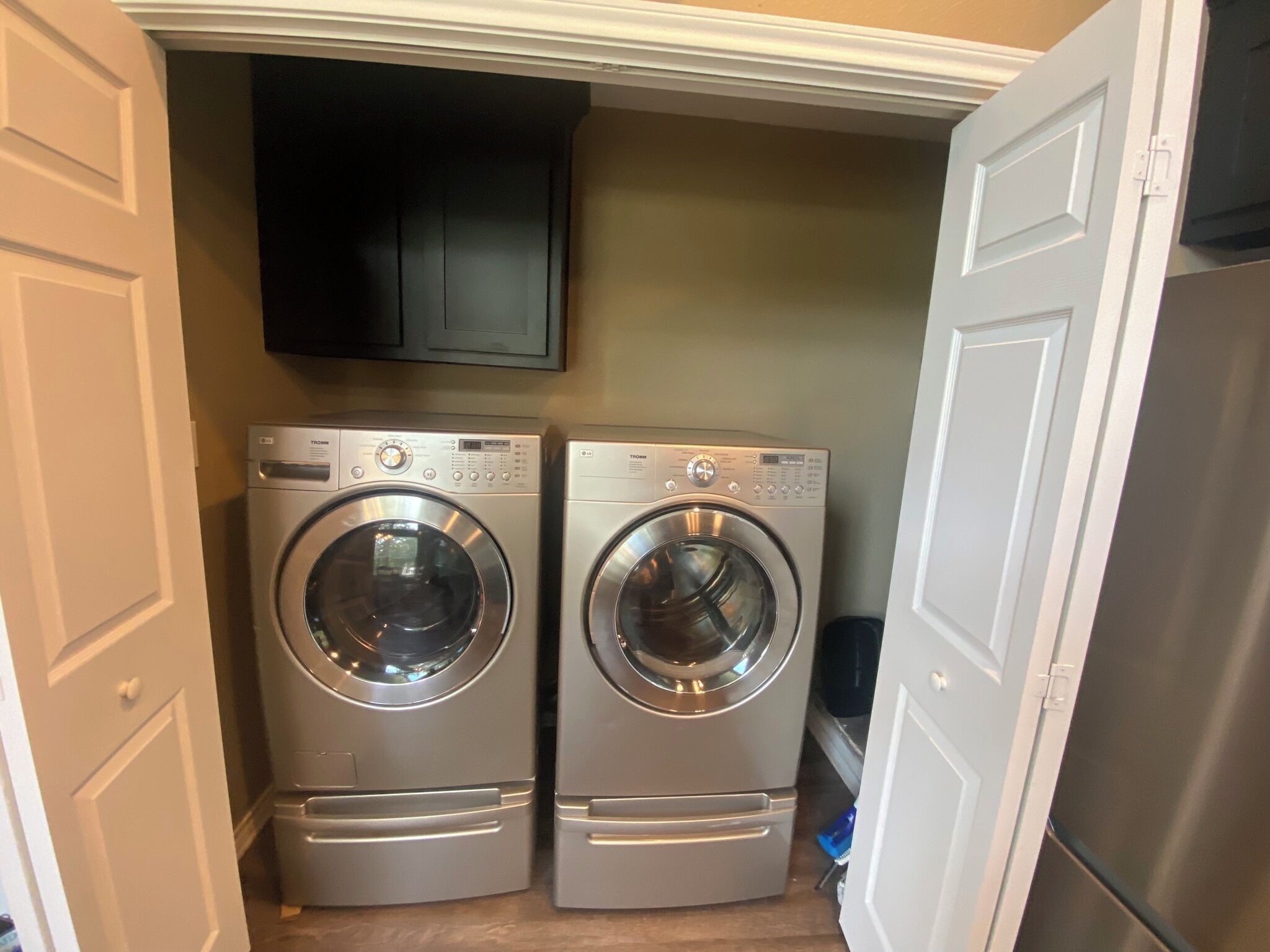 A laundry room with two front-loading washing machines and a flat-screen TV mounted on the wall.