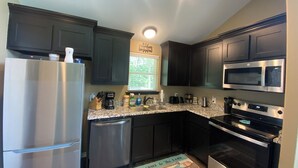 A modern kitchen with dark cabinets, stainless steel appliances, and a granite countertop. -  Weclome to Knot Shore  on Lake Texoma with boat parking (Pottsboro)