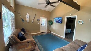 A living room with a ceiling fan, a TV mounted on the wall, and a door leading to another room. -  Weclome to Knot Shore  on Lake Texoma with boat parking (Pottsboro)