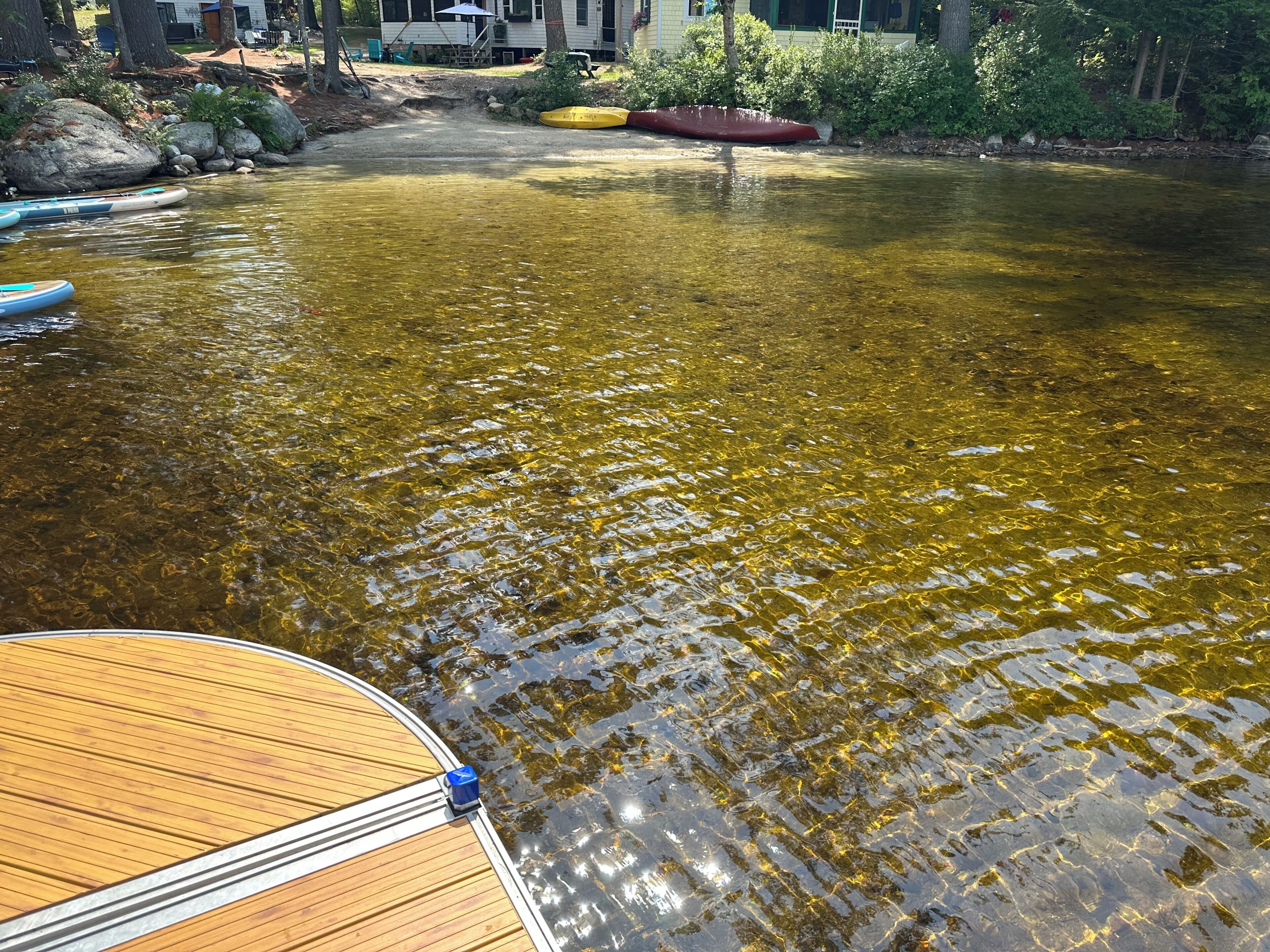 Un río con aguas claras, un muelle de madera y kayaks.