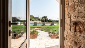An open door to a patio with a stone wall, a pathway, and outdoor seating. - Trulli Salsapariglia by Perle di Puglia (Putignano)