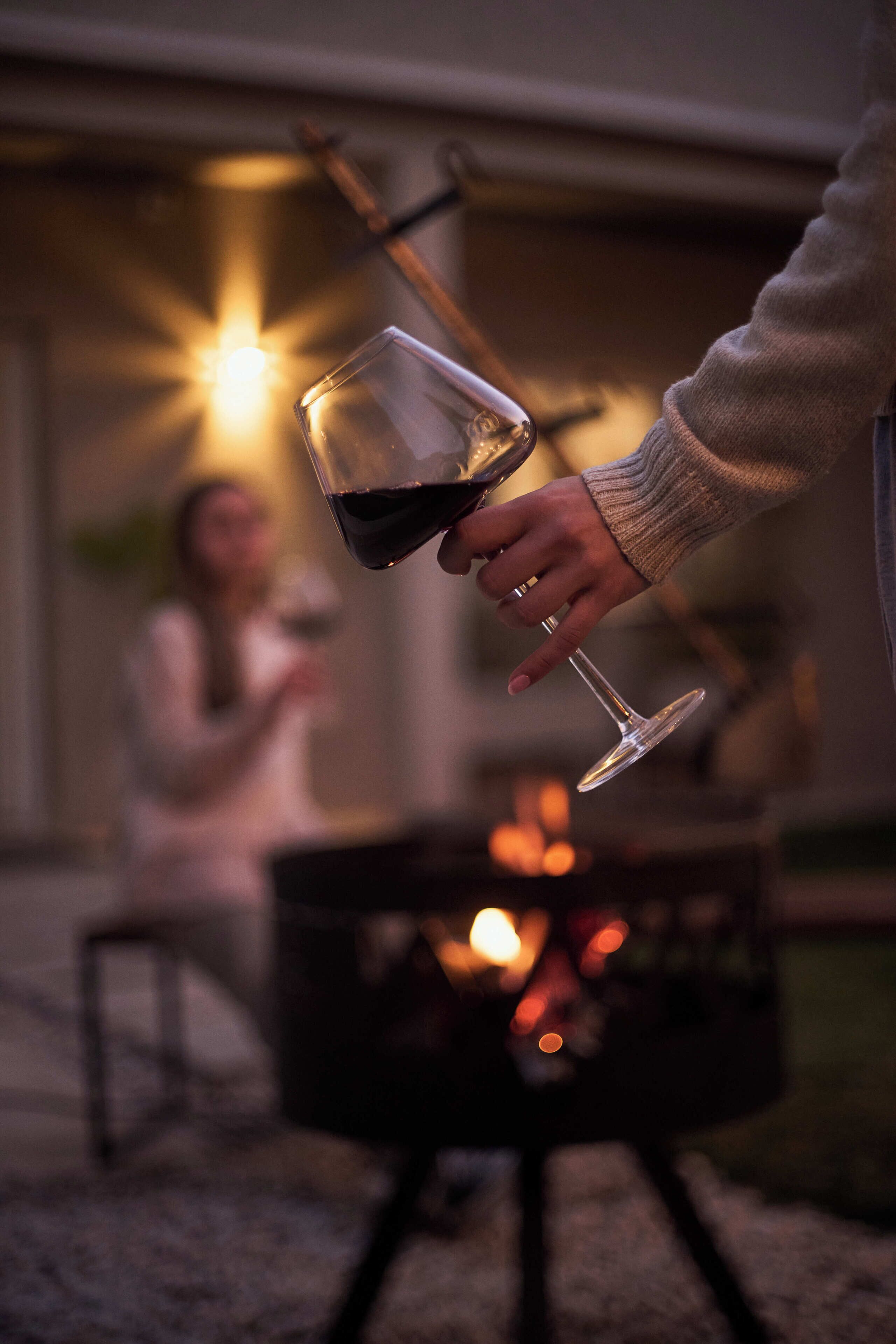 A person holding a wine glass with a fireplace in the background.