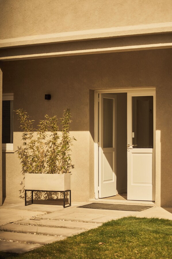 A building entrance with a door, a potted plant, and a small step leading to the door. - W&H Casa de Huespédes (Mendoza)