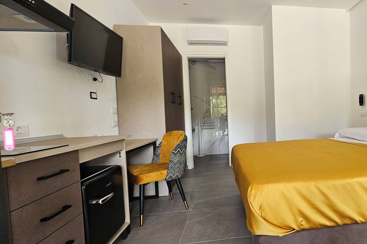 Ein modernes Hotelzimmer mit Bett, Schreibtisch, Stuhl und Fernseher.