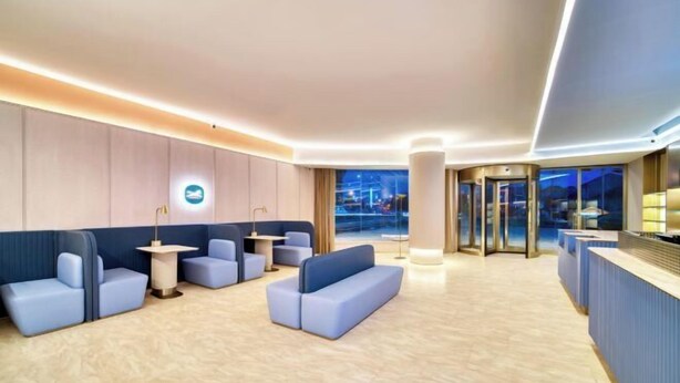 A modern hotel lobby with seating areas, a reception desk, and a view of the city at night. - HanTing Hotel (Cixi Guanhaiwei) (Cixi)