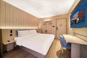 Une chambre d’hôtel équipée d’un lit, d’une table de chevet, d’une chaise et d’un bureau avec un ordinateur.