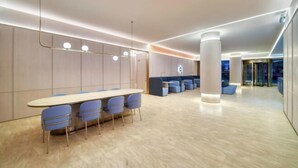 A modern conference room with a long table and blue chairs, a seating area with blue sofas, and a large pillar. - HanTing Hotel (Cixi Guanhaiwei) (Cixi)