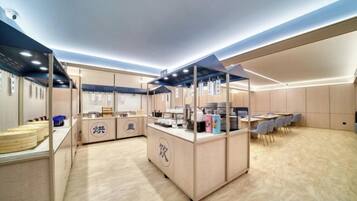 A modern kitchen with a central island, wooden flooring, and a seating area with tables and chairs.