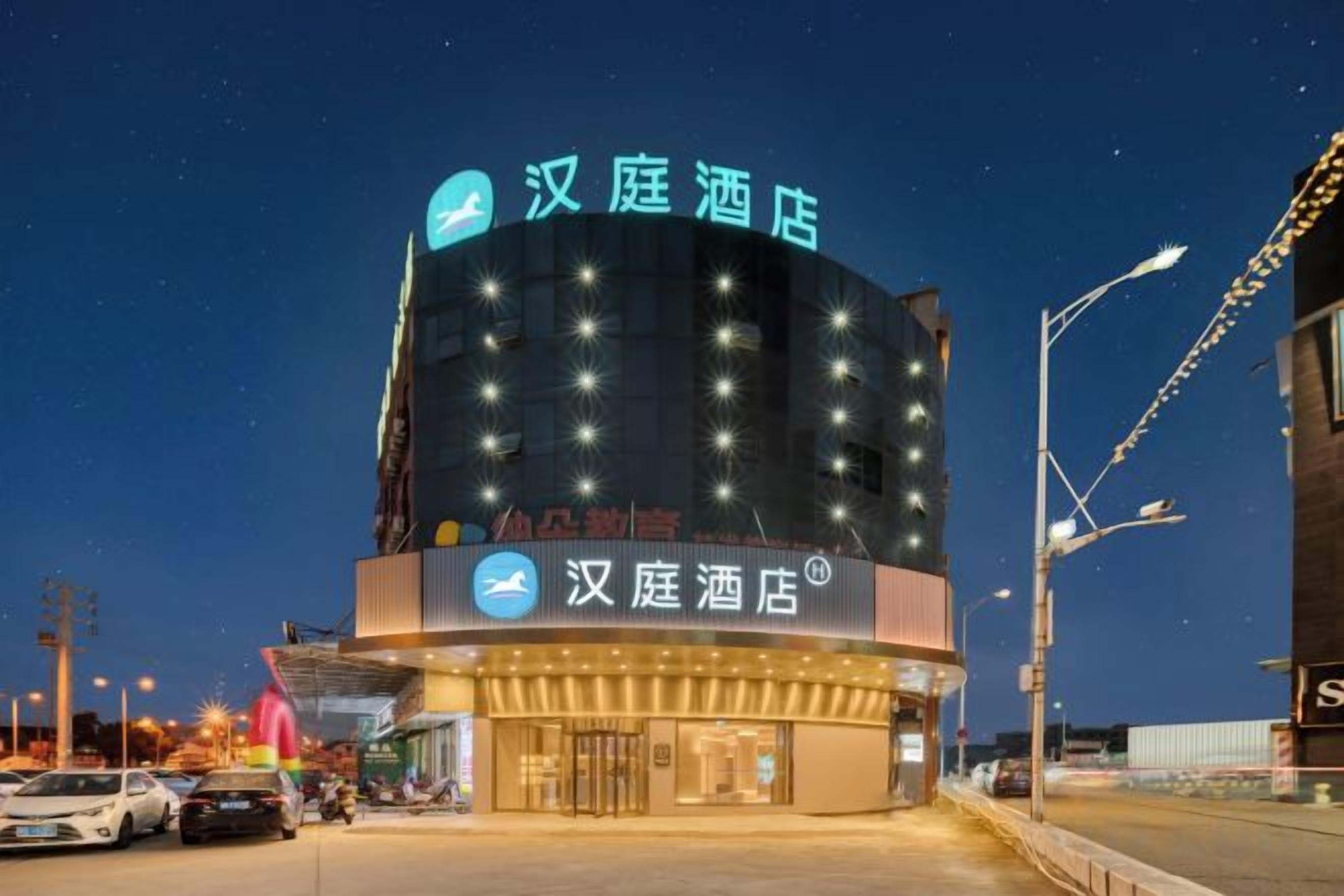 A hotel with a prominent sign, multiple floors, and a parking area.