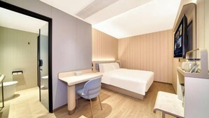 Une chambre d’hôtel moderne équipée d’un lit, d’un bureau, d’une chaise et d’un téléviseur.