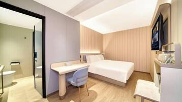 A modern hotel room with a bed, desk, chair, and a TV.