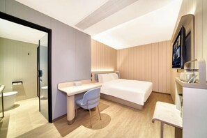 Une chambre d’hôtel moderne équipée d’un lit, d’un bureau, d’une chaise et d’un téléviseur.