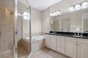 A modern bathroom with a glass-enclosed shower, a freestanding bathtub, and a large vanity with a mirror. - Beautiful Townhouse in Paseo (Fort Myers)