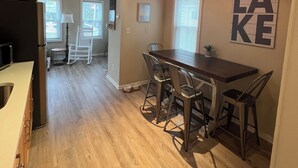 A spacious kitchen with wooden flooring, a dining area with bar stools, and a ceiling with exposed beams.