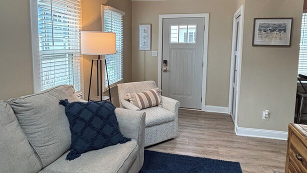 A living room with a sofa, armchair, lamp, and a clock on the wall.