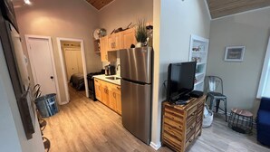 A modern kitchen with wooden cabinets, stainless steel appliances, and a built-in TV.