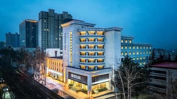 A multi-story hotel with a modern design, featuring a prominent entrance and a visible restaurant on the ground floor.
