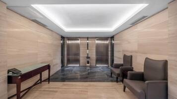 A modern elevator lobby with a marble floor, a reception desk, and a seating area.