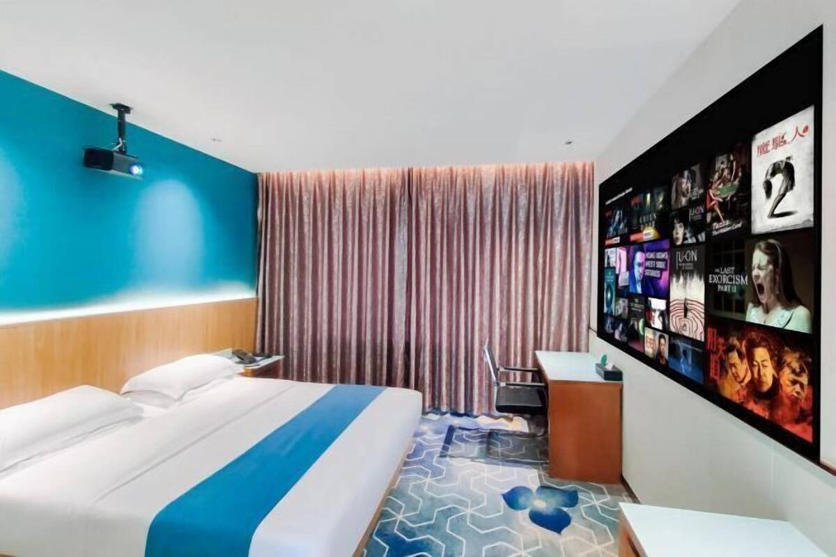 A hotel room with a bed, a desk, a TV wall, and curtains.
