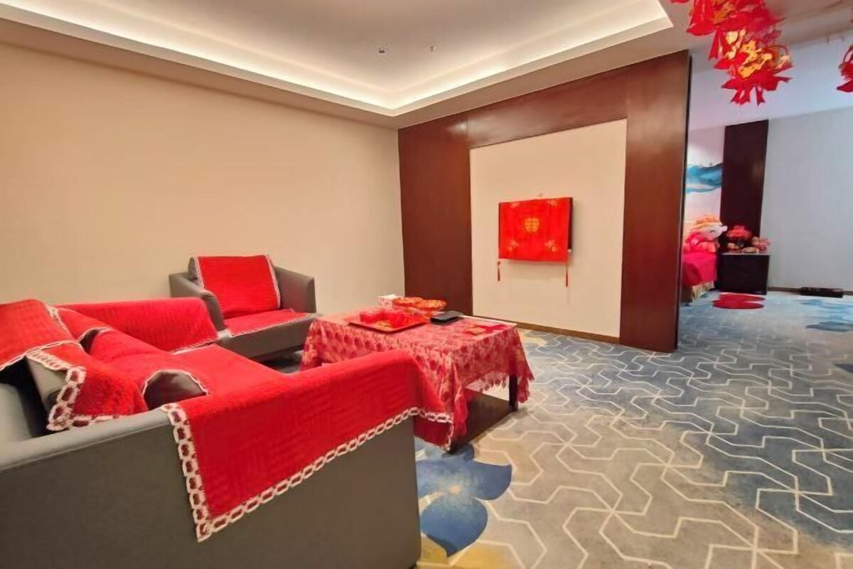 A modern room with a sofa set, a small table with a red tablecloth, and a wall with a red painting.