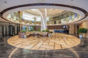 A spacious lobby with a central seating area, a glass atrium, and a modern design. - Rongcheng Celebrity Hotel (Rongcheng High Speed Rail Station Shop) (Rongcheng)