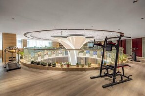 Un gimnasio con un diseño circular central, equipamiento de ejercicio y plantas en macetas.
