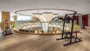 Un gimnasio moderno con diseño circular, una pared de vidrio central y diverso equipo de ejercicio.