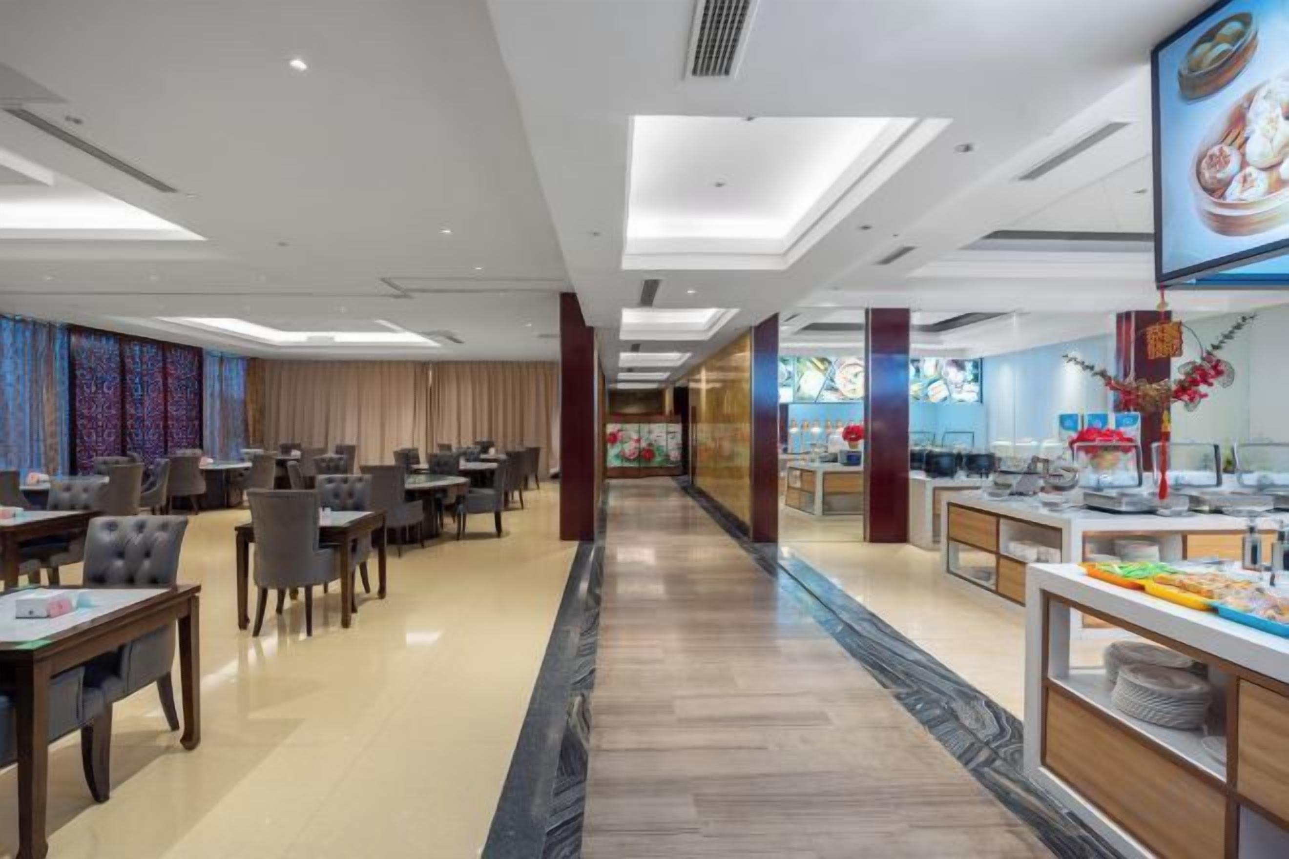 A hotel dining area with tables and chairs, a buffet counter, and a view of the lobby.