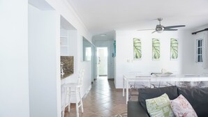 Un saló modern amb un sofà negre, una taula de dinar i un ventilador de sostre.