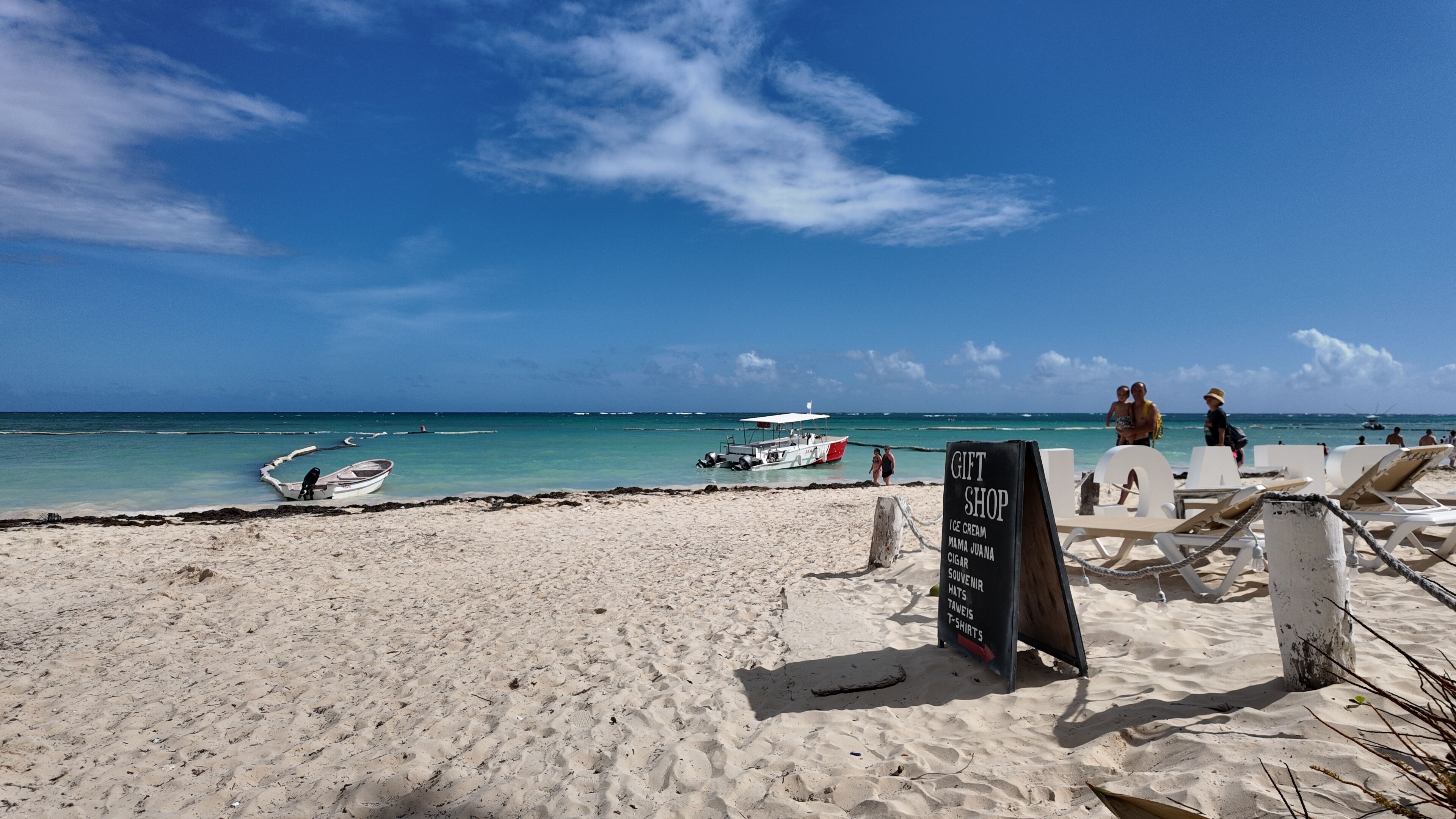 Ein Strand mit einem Souvenirladen, einem Boot und Personen im Sand.