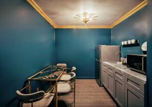 A compact kitchen with a dining table and chairs, a refrigerator, a microwave, and a sink. - The Fainting Couch Boutique Hotel (Cobb)