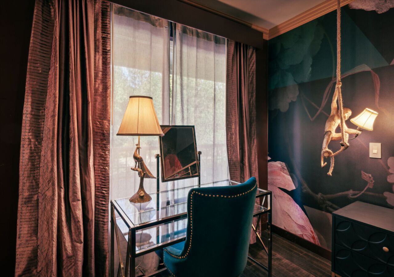 A room with a desk, chair, and a large window with curtains.