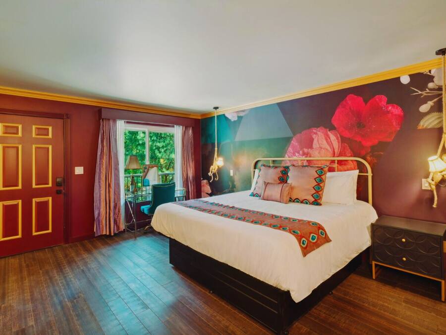 Ein Schlafzimmer mit einem großen Bett, einem Nachttisch, einer Tür mit ungewöhnlichem Design und einem Wandgemälde.