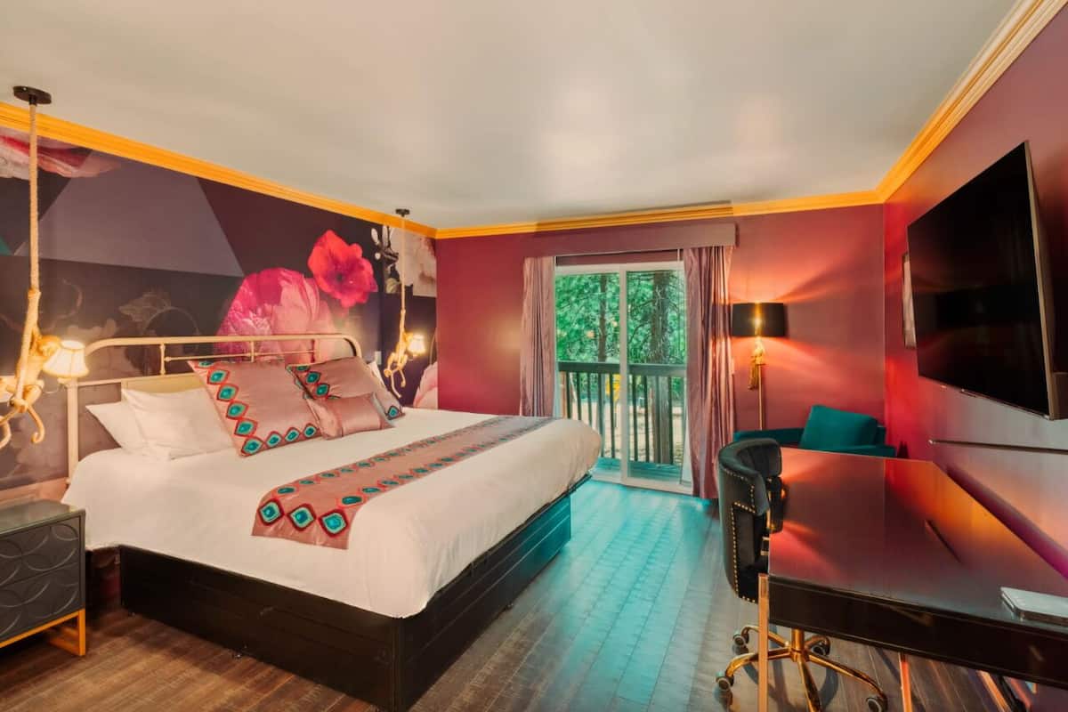 A modern hotel room with a large bed, a desk, and a TV.