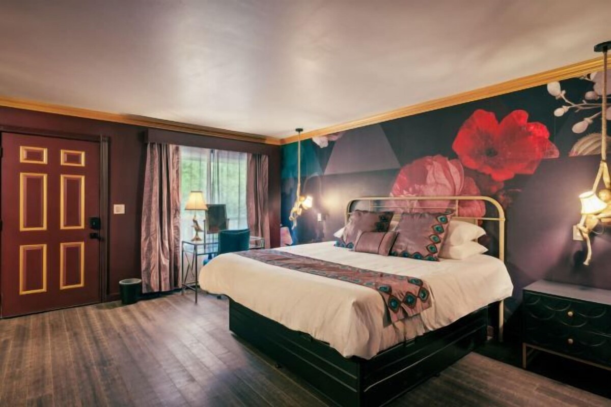 A bedroom with a bed, a nightstand, a lamp, and a door.