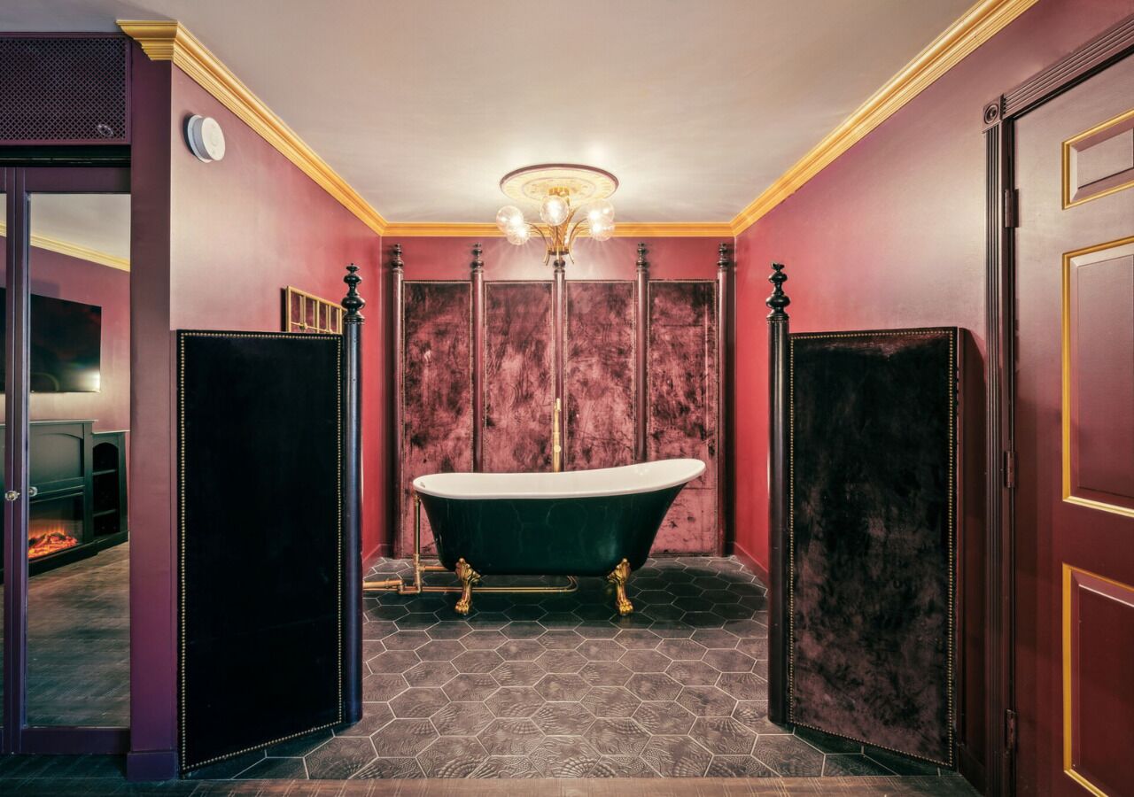 A room with a freestanding bathtub, a fireplace, and a chandelier.