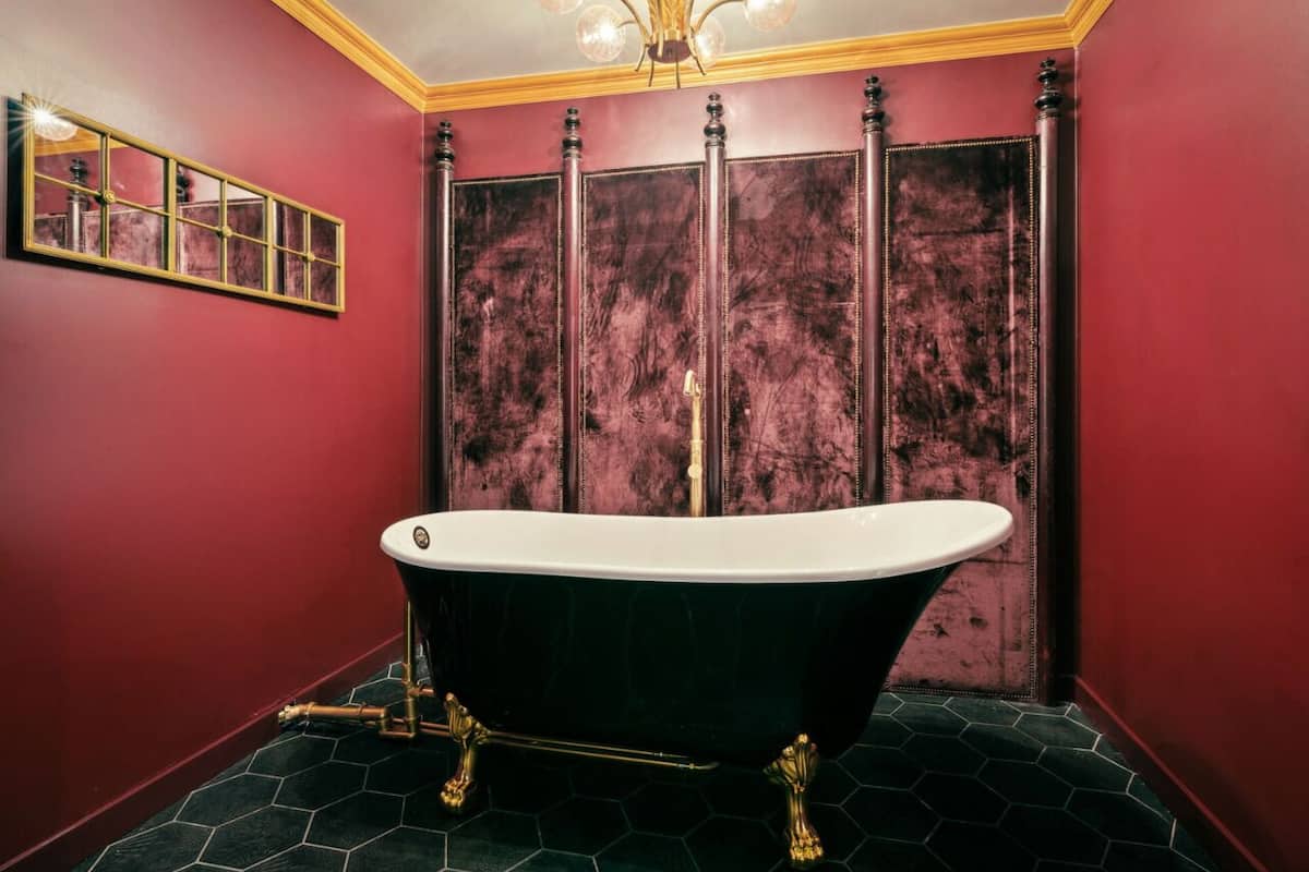 A room with a freestanding bathtub, a mirror, and a decorative panel.