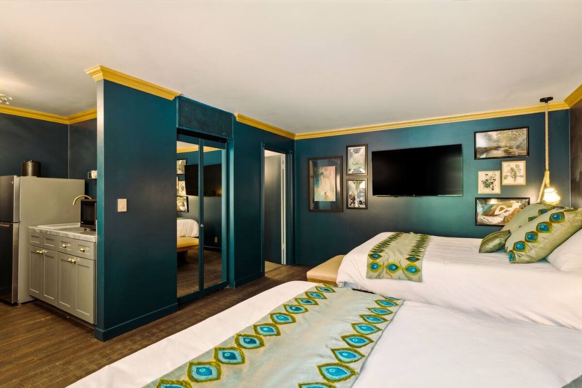 A hotel room with a bed, a desk, and a kitchenette.