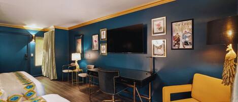 A hotel room with a bed, desk, chair, and a television on the wall.