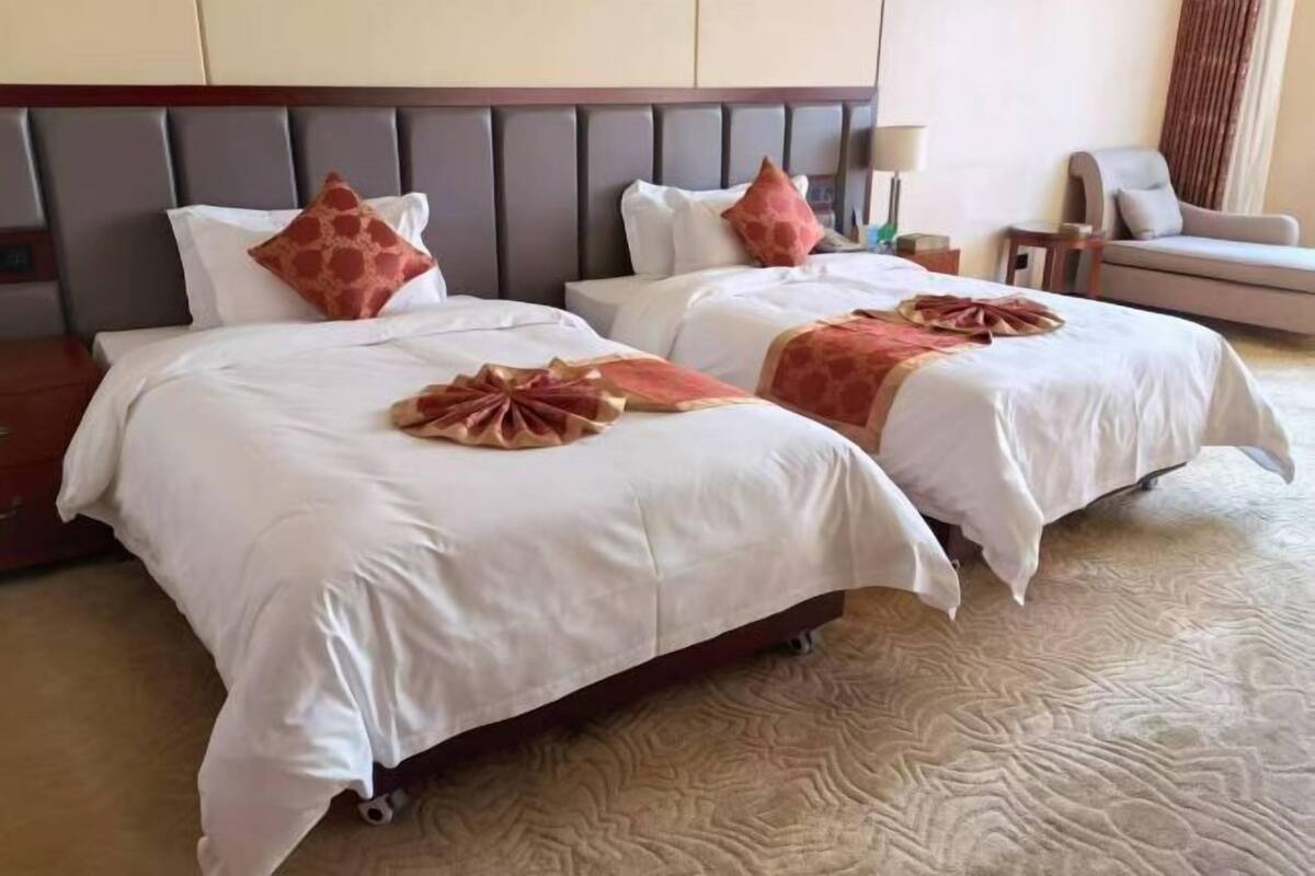 Ein Hotelzimmer mit zwei Betten, einem Kopfteil, einer Couch und einer Lampe.