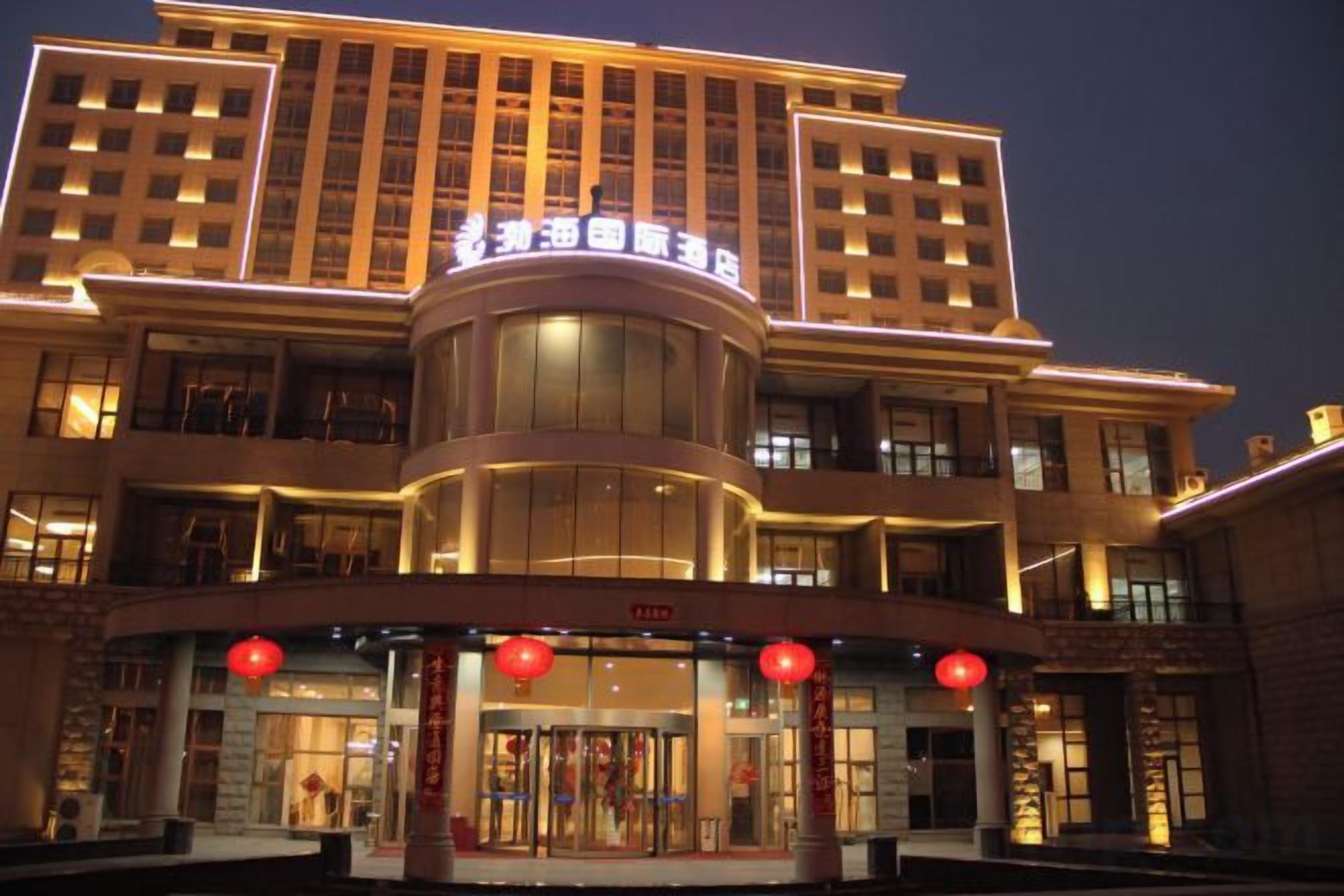Un hotel de varios pisos con una entrada destacada, un atrium central y una serie de balcones en los pisos superiores.