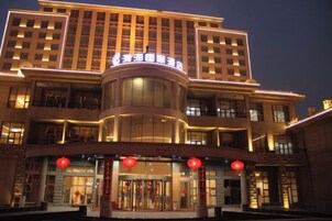 Un hotel de varios pisos con una entrada destacada, un atrium central y una serie de balcones en los pisos superiores.