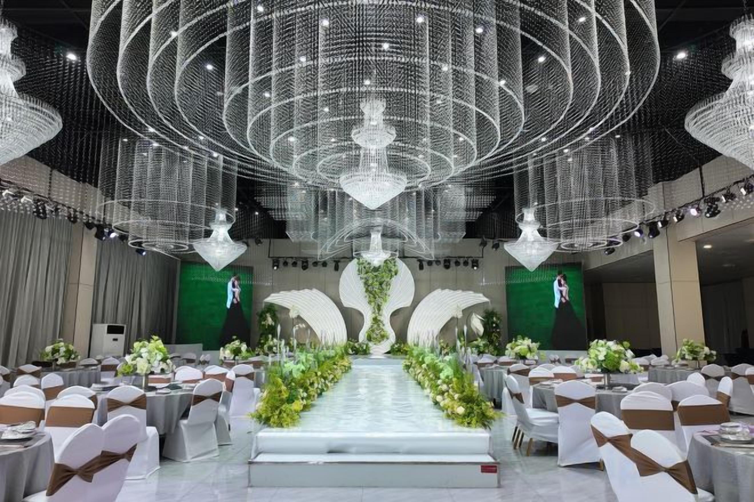 Un salón de banquetes con asientos escalonados, un escenario central y una gran lámpara de araña.