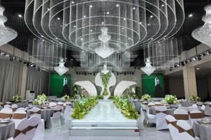 Un salón de banquetes con asientos escalonados, un escenario central y una gran lámpara de araña.