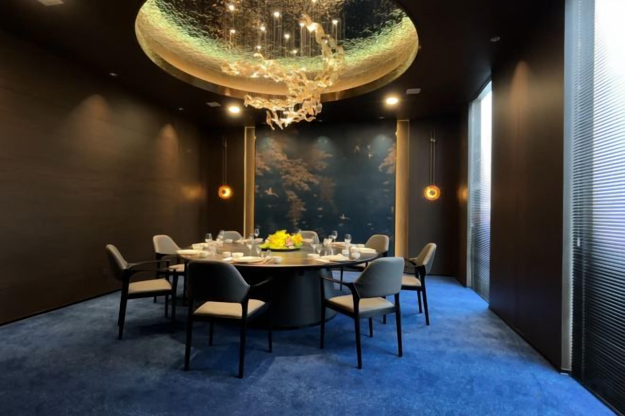 A conference room with a round table, chairs, and a chandelier.