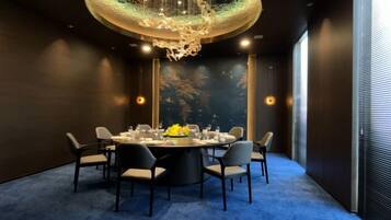 A conference room with a round table, chairs, and a chandelier.